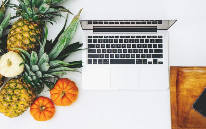 Una lap top rodeada de muchas heramientas saludables como frutas y verduras